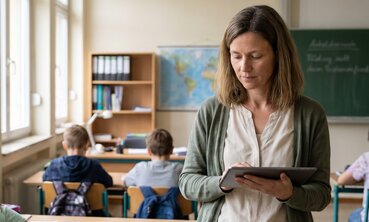 Lehrerin erfasst im Klassenzimmer auf einem Tablet die Anwesenheit im digitalen Klassenbuch